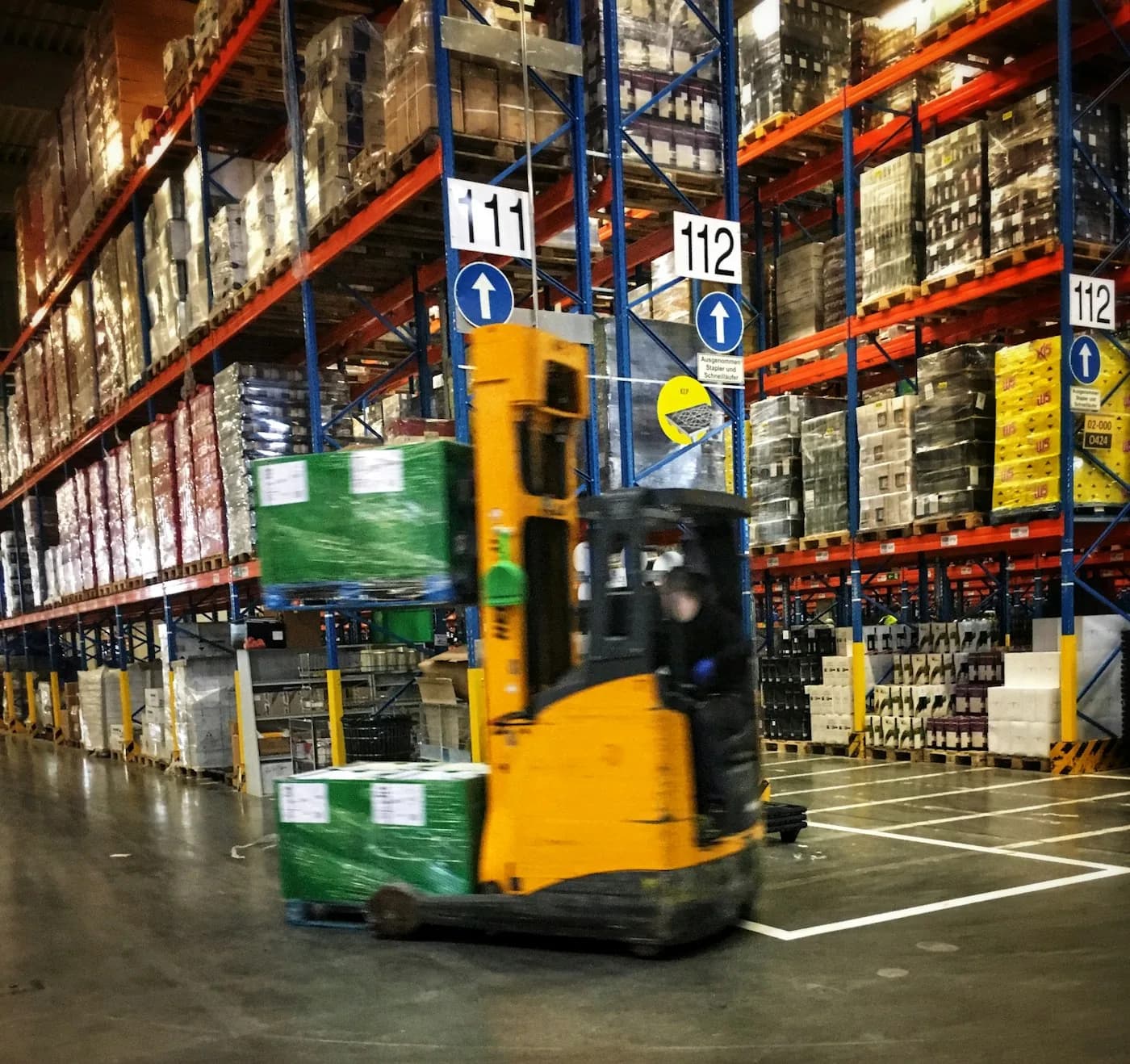 Forklift moving inventory inside a logistics warehouse
